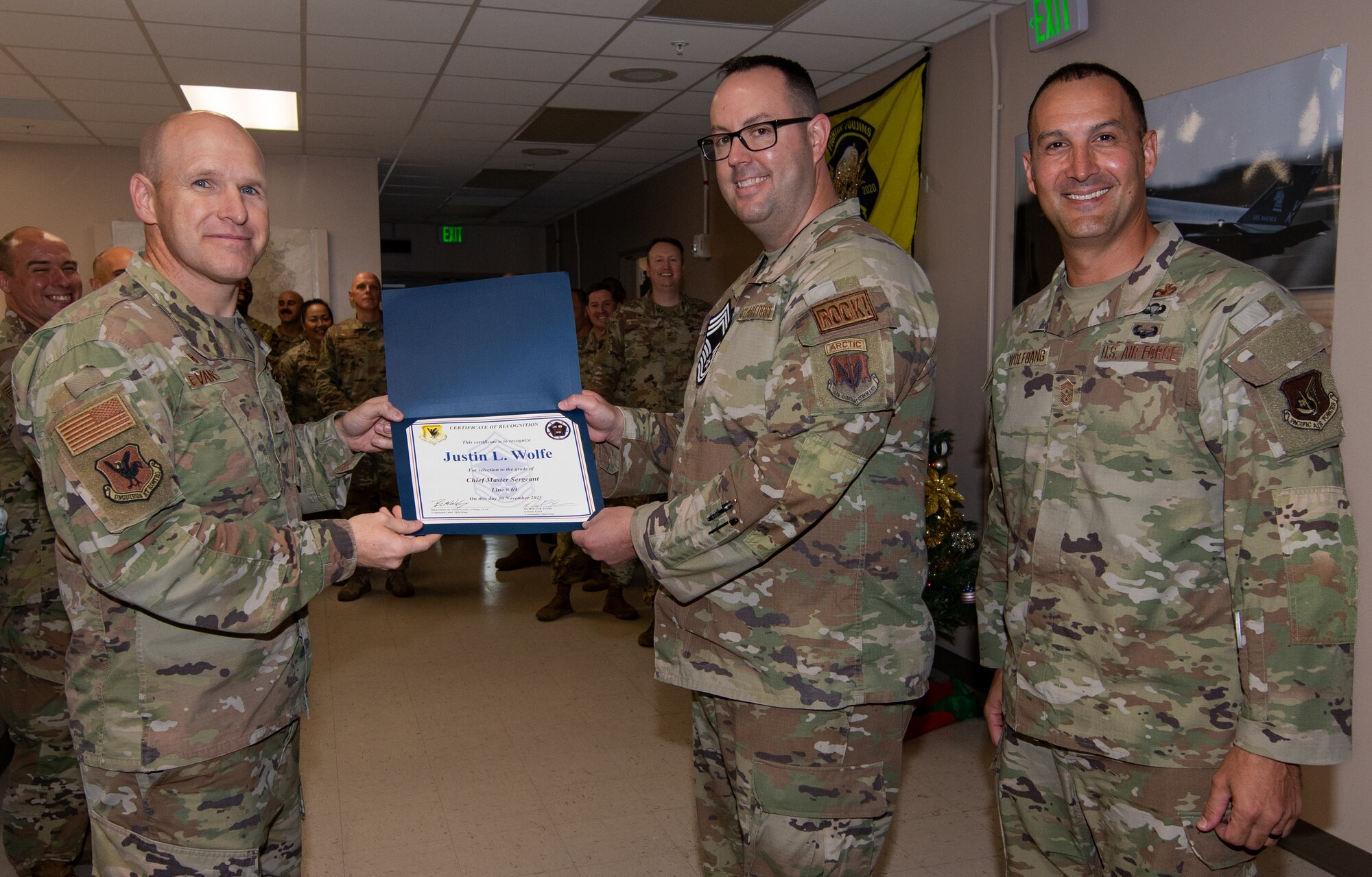Three U.S. Air Force service members pose with a certificate.