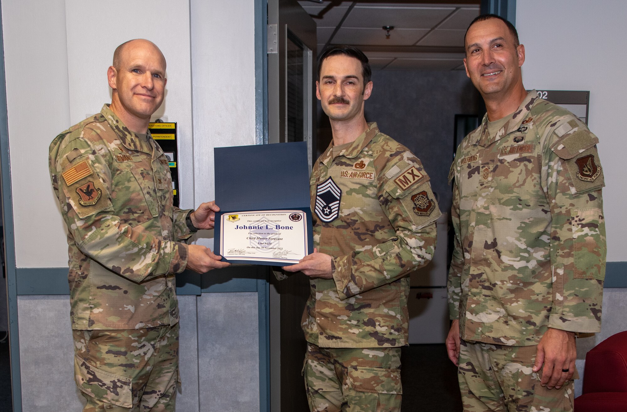 Three U.S. Air Force service members pose with a certificate.