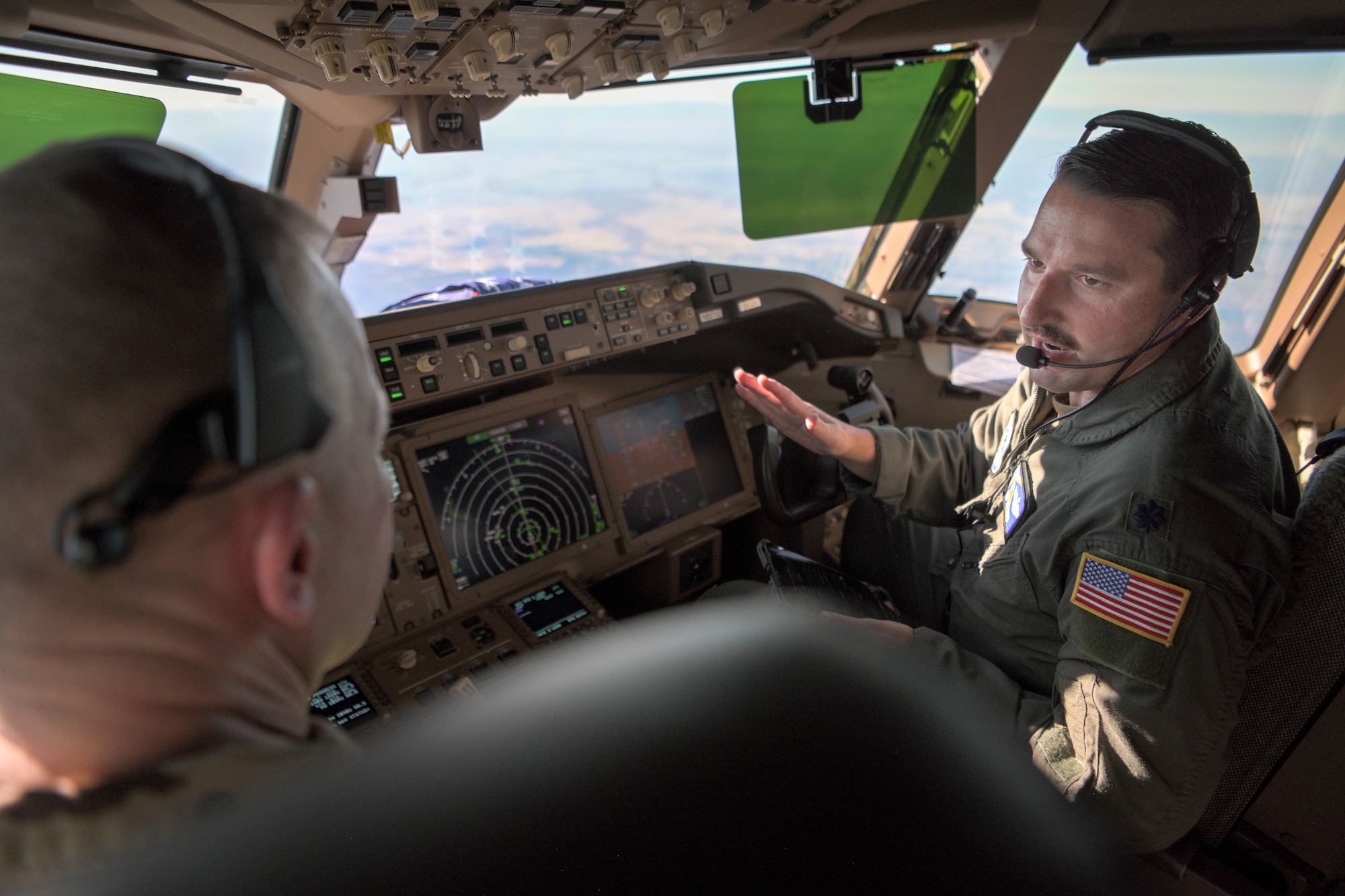 Lt. Col. Fisher speaks to Brig. Gen. Salmi in the pilot seats of a KC-46A Pegasus aircraft.