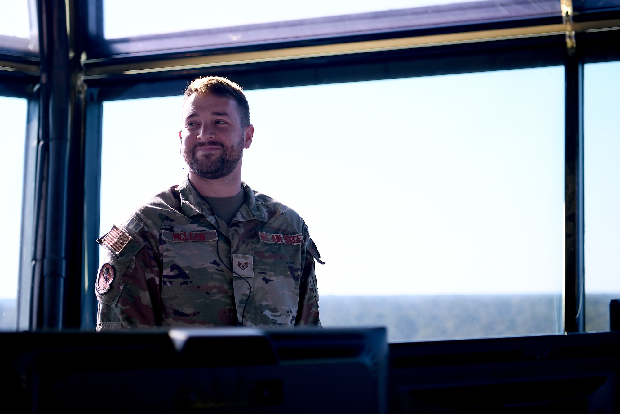 A man in uniform looks to the left of the camera, smiling.