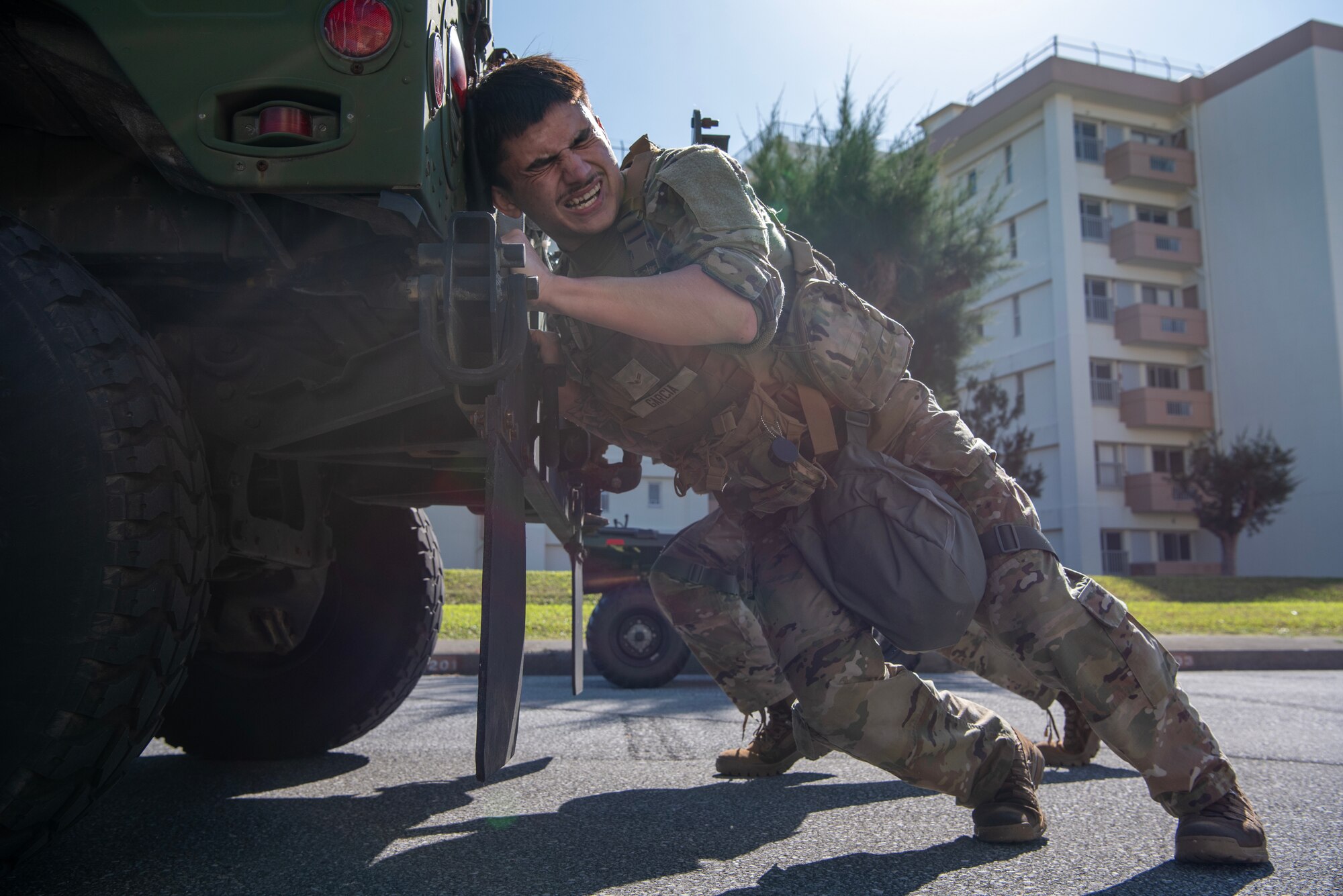 military members pushing a humvee