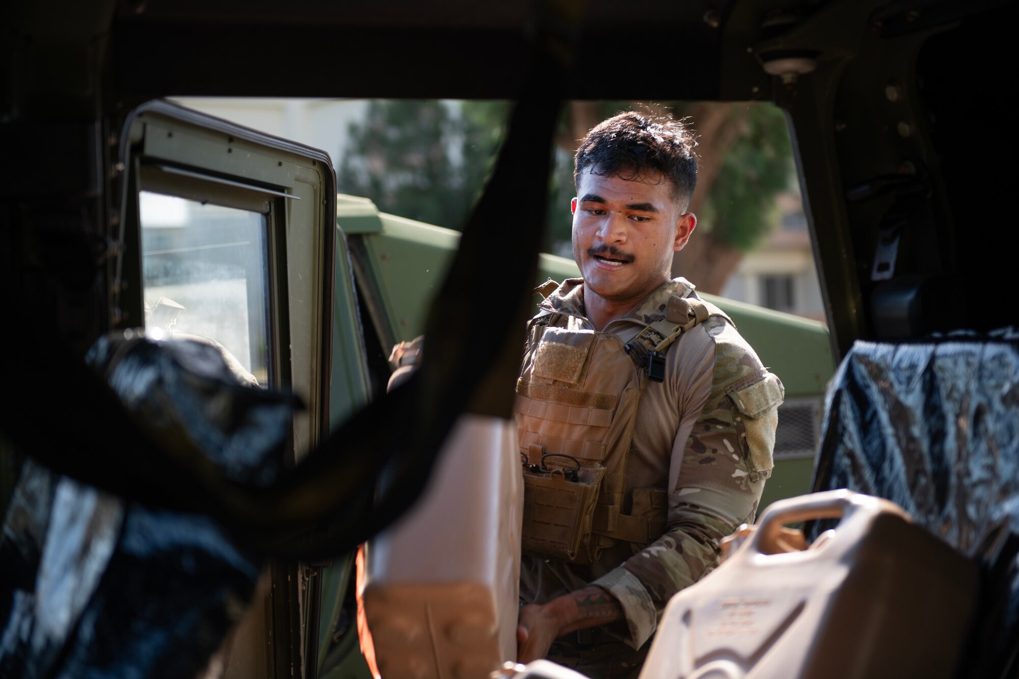 military member loads a gas tank container into a humvee vehicle