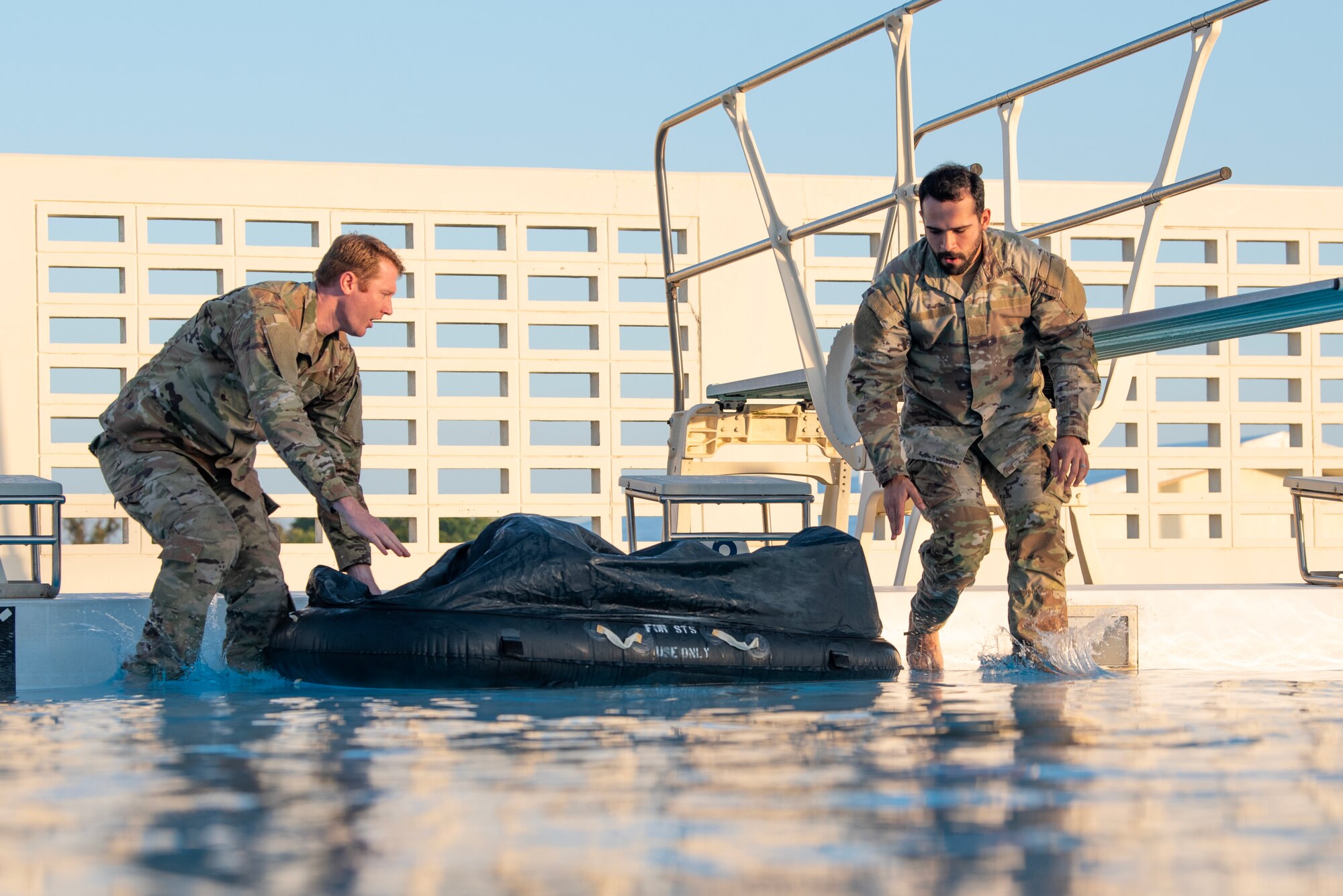 military members jump into a pool in uniform