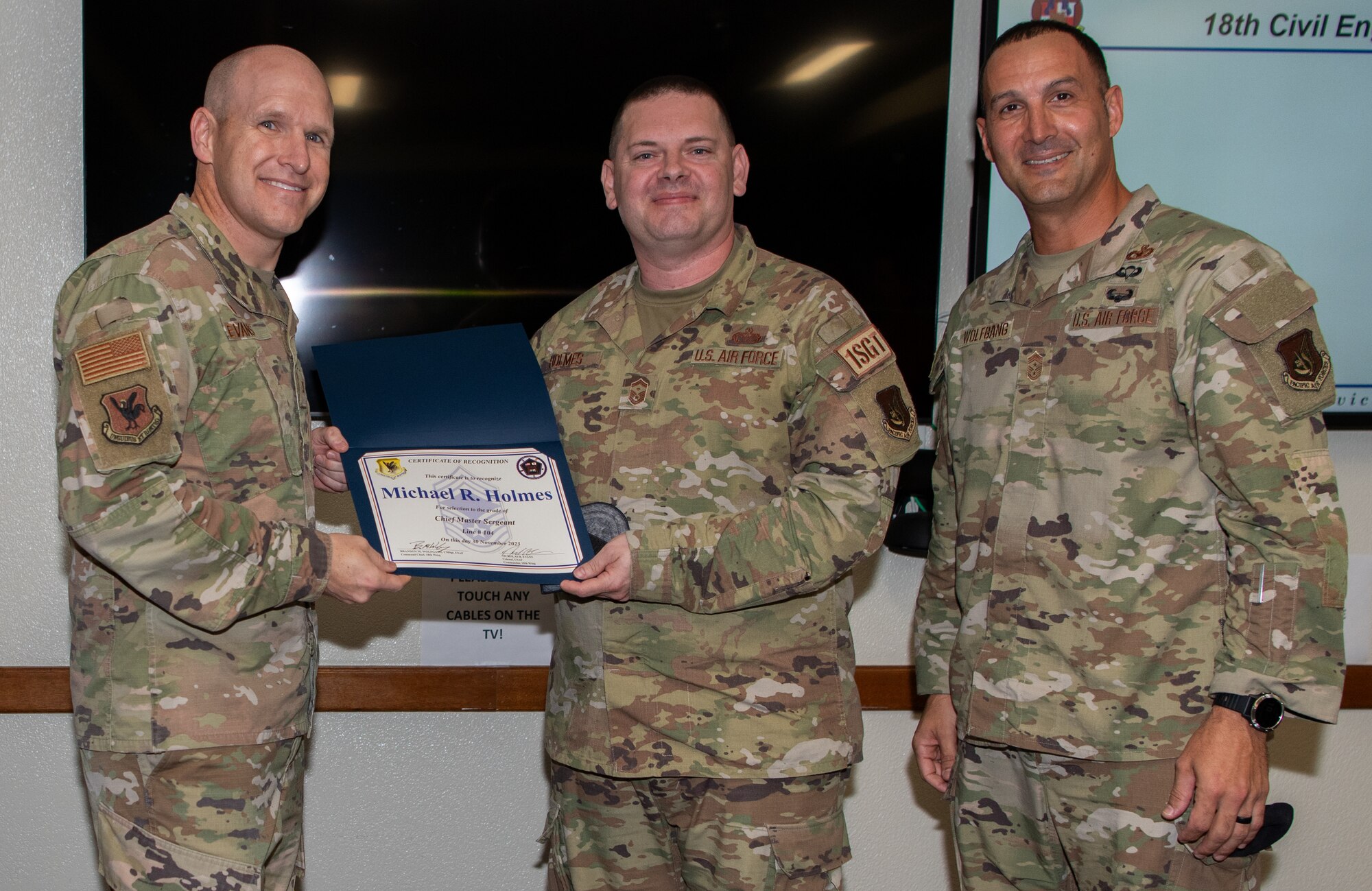 Three U.S. Air Force service members pose with a certificate.