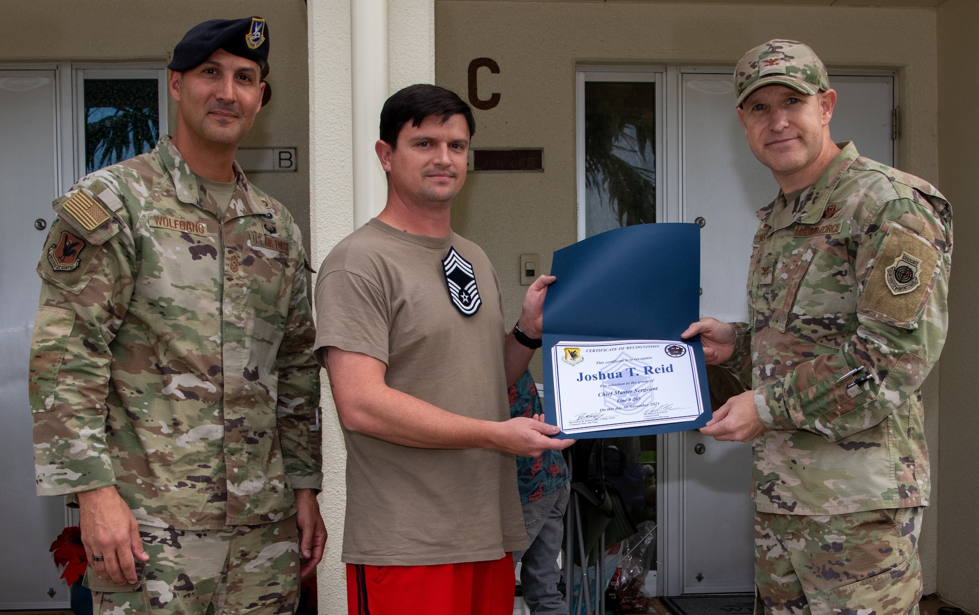 Three U.S. Air Force service members pose with a certificate.