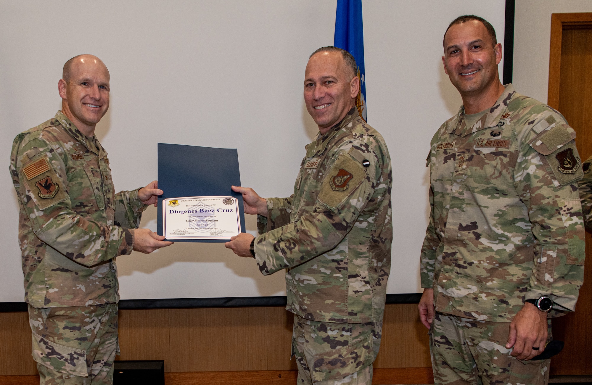 Three U.S. Air Force service members pose with a certificate.