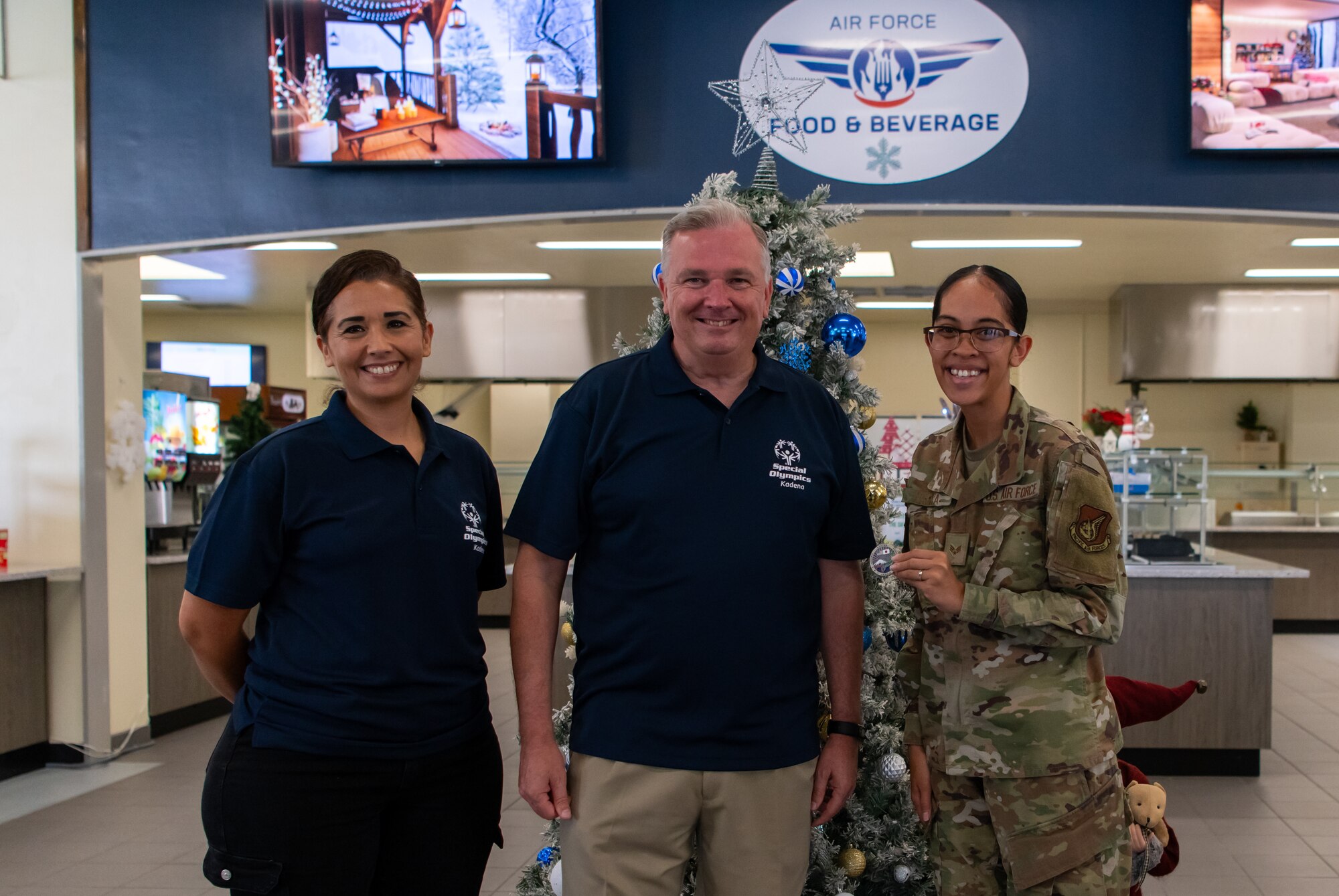 Three service members pose with a coin