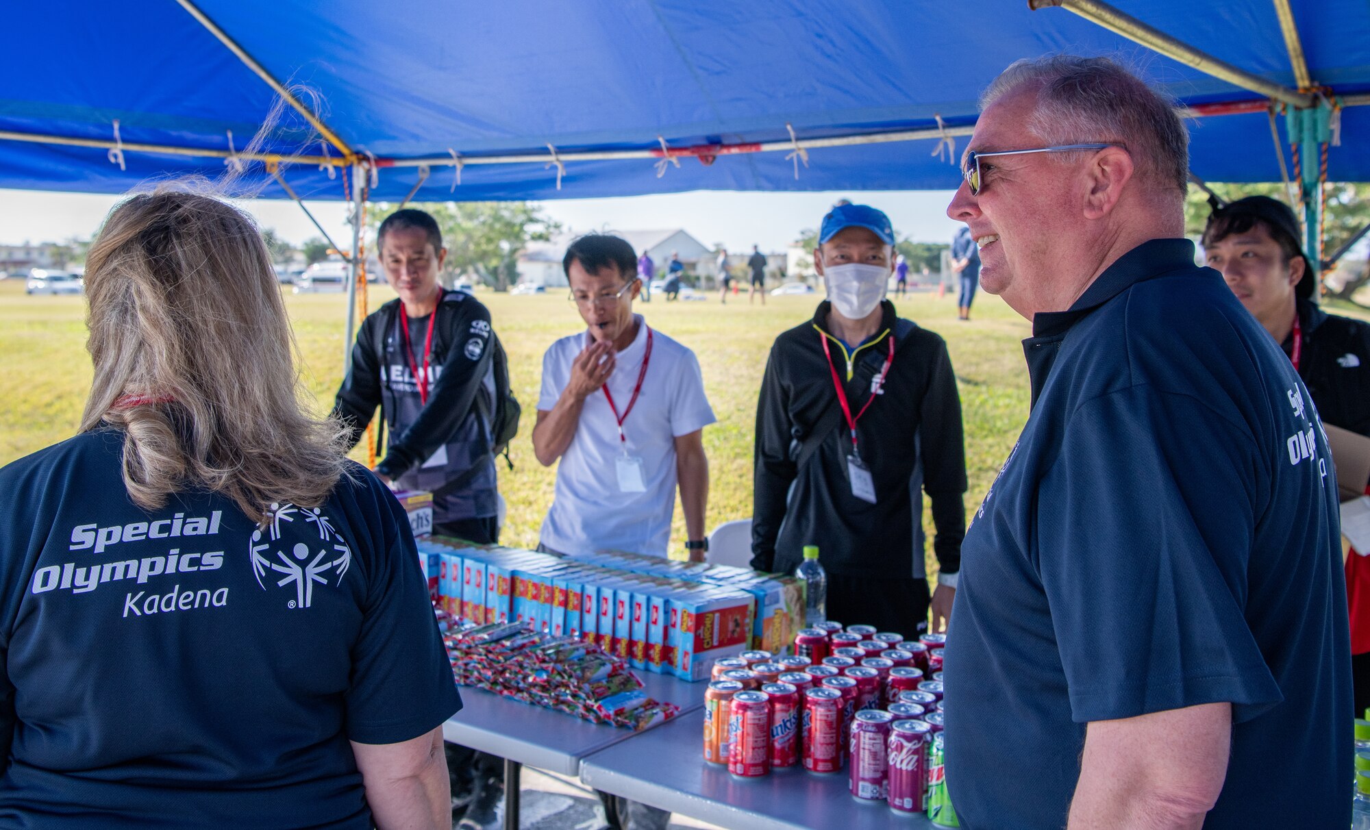 Volunteers stand under a tent.