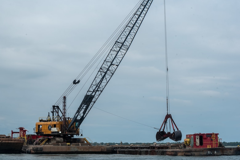 A crane on a barge uses a clamshell scoop to dredge sediment in a harbor in Erie, Pa.