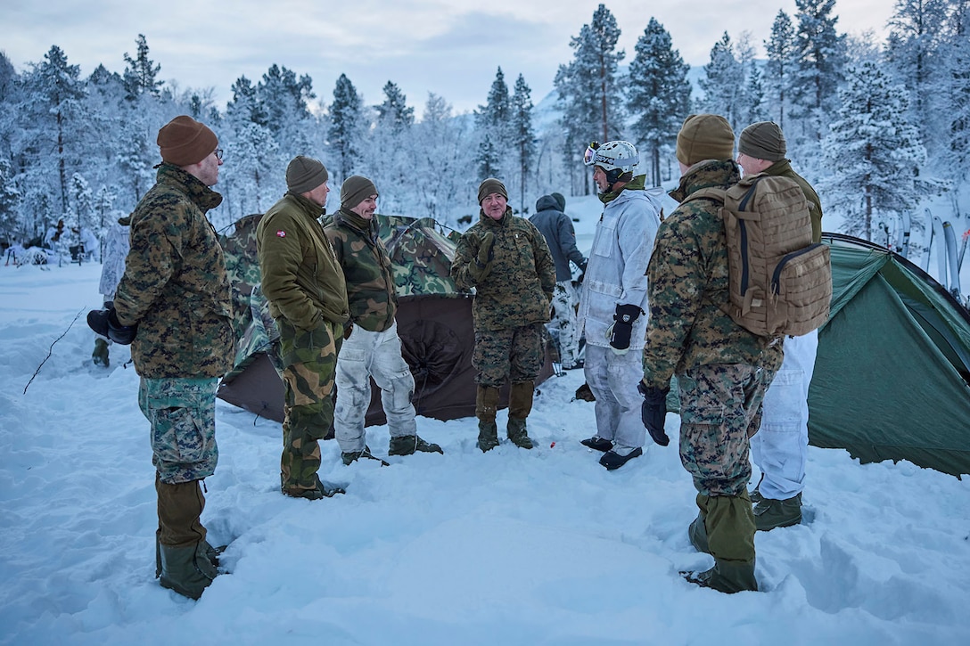 An officer speaks to service members during a snowy training mission.