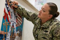 Petty Officer 2nd Class Jessica Smith, assigned to CLDJ’s Public Works Department, paints a mural at Camp Lemonnier, Djibouti, Dec. 12, 2023.