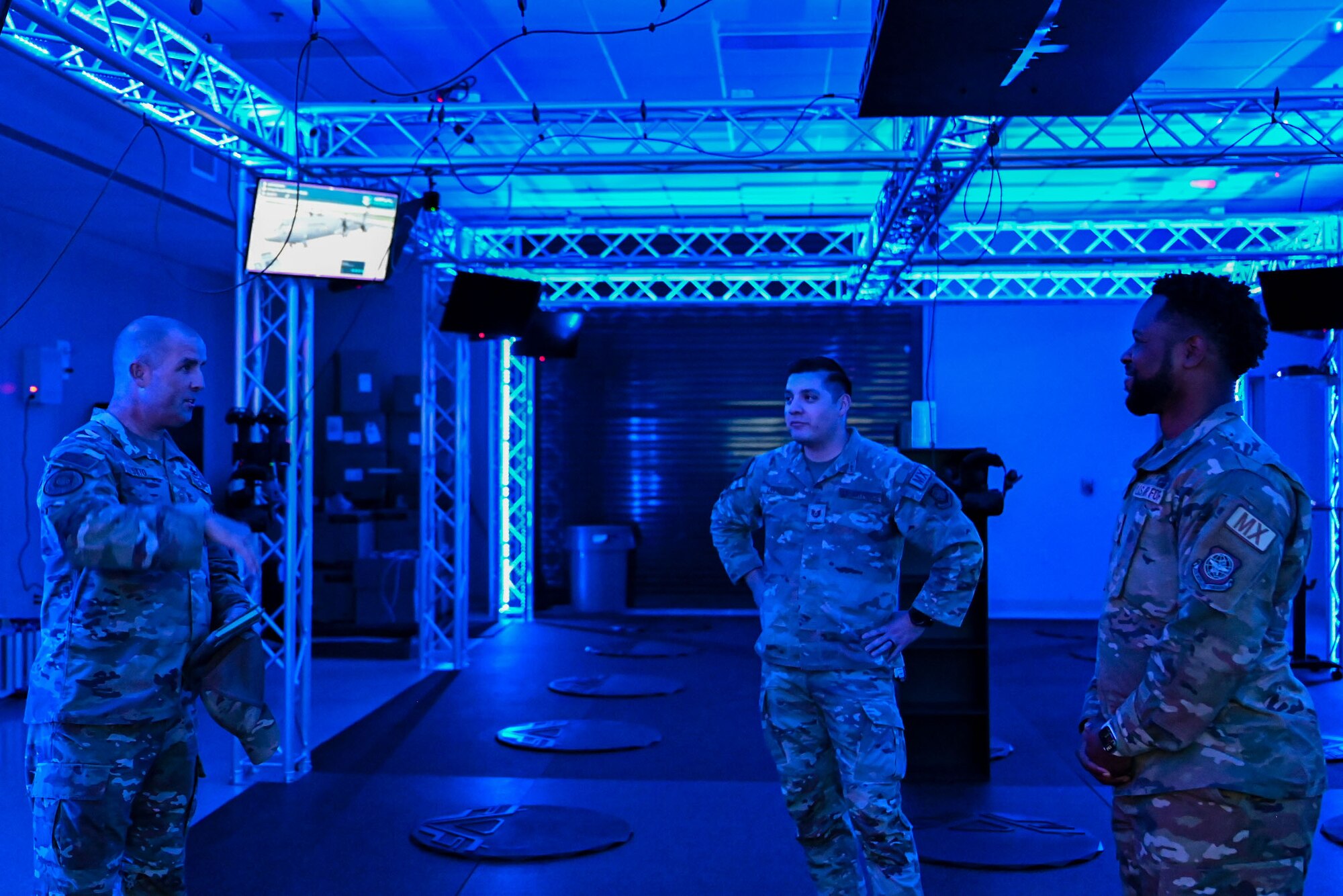 Three military members talk in a blue room.