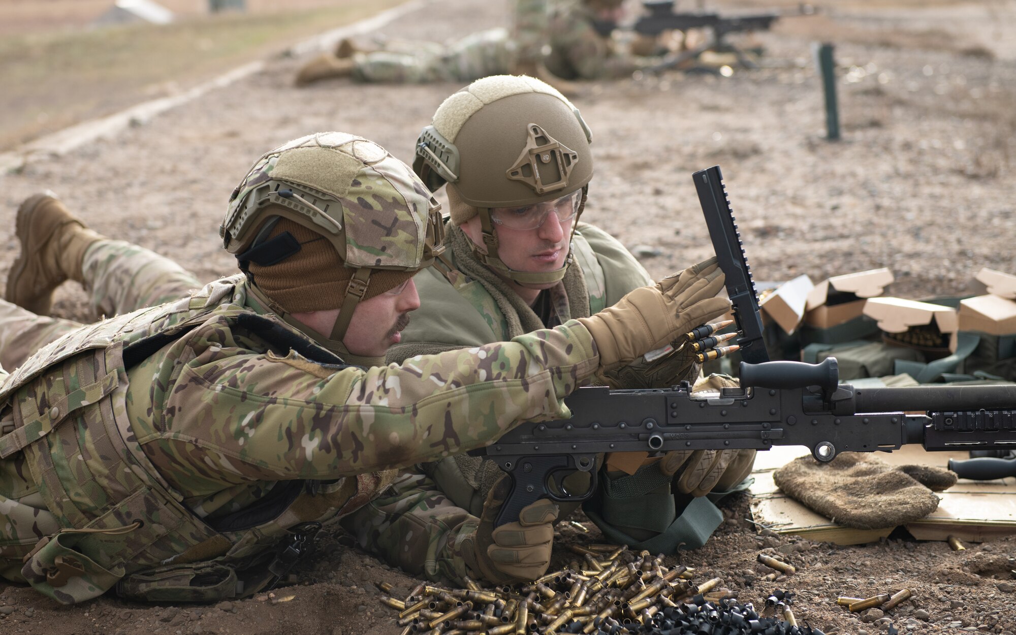 Two men look at machine gun.