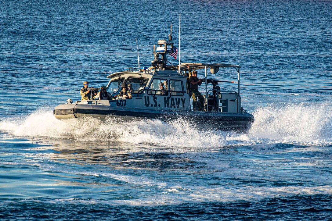 Sailors travel through a body of water in a boat; some operate mounted weapons.