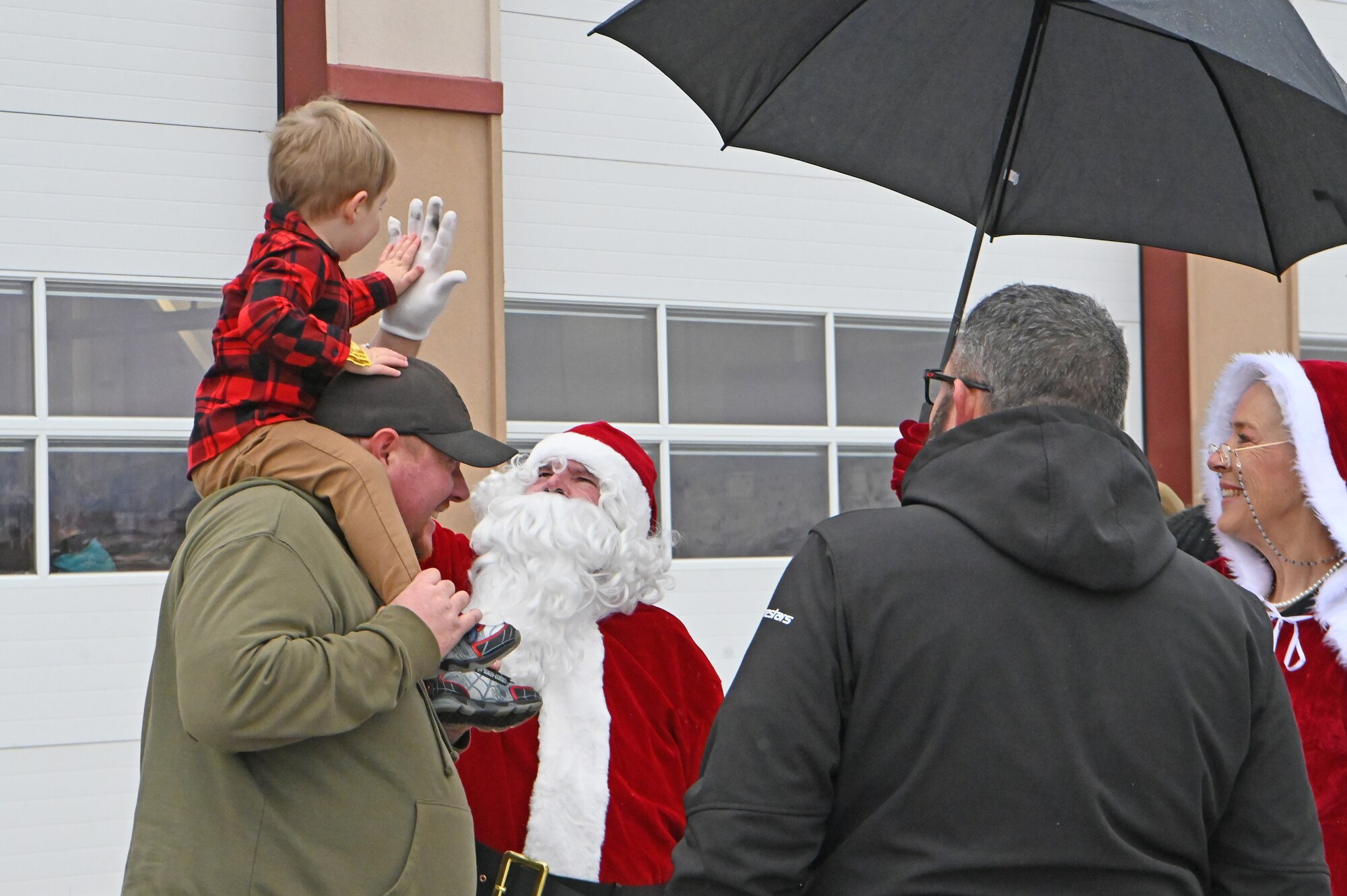 Santa reaches up to high five an excited child during the annual Children's Christmas Festival on Kingsley Field.