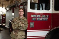 Airman 1st Class Stephen Warren, a firefighter with the 142nd Civil Engineer Squadron, poses next to a fire engine at Portland Air National Guard Base, Ore., November 5, 2023.