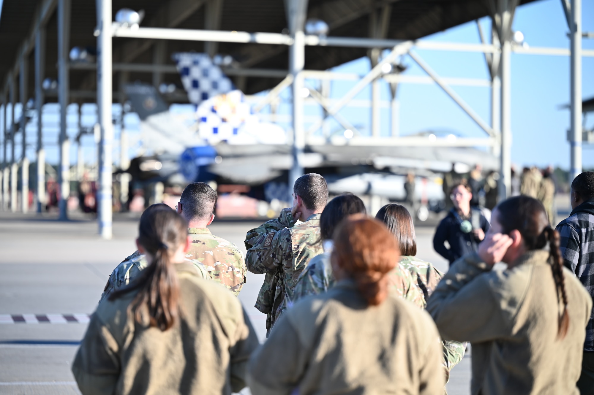 People walk onto flightline with jets in the background