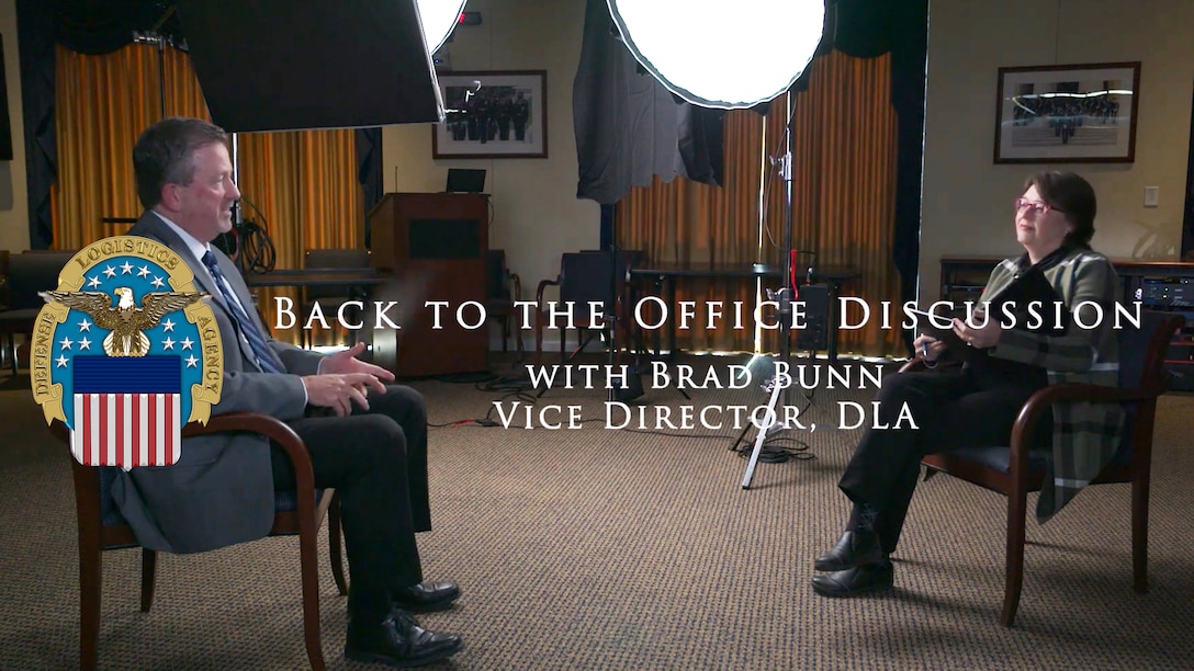 Two people sit in chairs, facing each other, during a video interview.