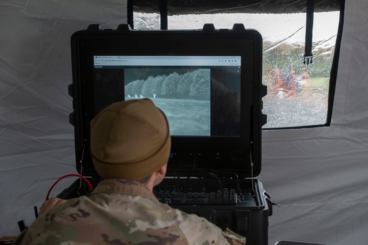 A service member in uniform looks at a computer screen.
