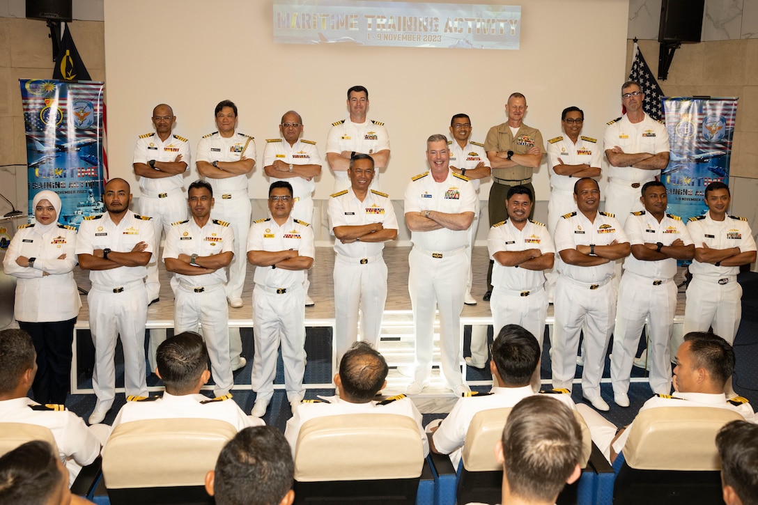 U.S. Navy Rear Adm. Chris Stone, Commander, Expeditionary Strike Group Seven, Task Force 76/3, Col. Thomas Siverts, Marine Rotational Force-Southeast Asia, I Marine Expeditionary Force, U.S. Navy Sailors assigned to USS Manchester (LCS 14), Sailors from Destroyer Squadron 7, and Royal Malaysian Navy sailors with Western Fleet Command pose for a photo during the opening ceremony of Maritime Training Activity Malaysia onboard RMN Lumut Naval Base, Lumut, Malaysia, Nov. 1, 2023. The ceremony marked the beginning of MTA Malaysia and was attended by sailors from the Royal Malaysian Navy, U.S. Navy, and U.S. Marines. MTA Malaysia 2023 highlights the 4th iteration of this series as one of many exercises that allow the U.S. and Royal Malaysian navies to work together, enhancing maritime security and capabilities in the full range of maritime warfare. MRF-SEA is a Marine Corps Forces Pacific operational model, which involves planned exchanges with subject matter experts, promotes security goals with Allies and partners and positions I MEF forces west of the International Date Line. (U.S. Marine Corps photo by Staff Sgt. Kai W. Huber)