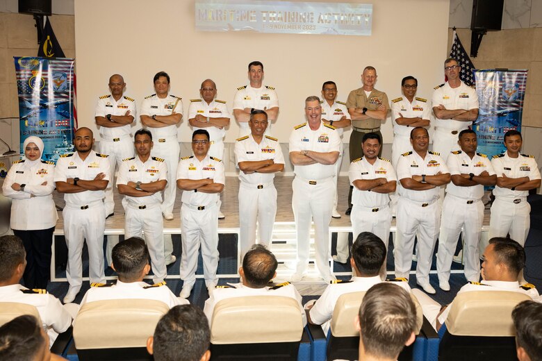 U.S. Navy Rear Adm. Chris Stone, Commander, Expeditionary Strike Group Seven, Task Force 76/3, Col. Thomas Siverts, Marine Rotational Force-Southeast Asia, I Marine Expeditionary Force, U.S. Navy Sailors assigned to USS Manchester (LCS 14), Sailors from Destroyer Squadron 7, and Royal Malaysian Navy sailors with Western Fleet Command pose for a photo during the opening ceremony of Maritime Training Activity Malaysia onboard RMN Lumut Naval Base, Lumut, Malaysia, Nov. 1, 2023. The ceremony marked the beginning of MTA Malaysia and was attended by sailors from the Royal Malaysian Navy, U.S. Navy, and U.S. Marines. MTA Malaysia 2023 highlights the 4th iteration of this series as one of many exercises that allow the U.S. and Royal Malaysian navies to work together, enhancing maritime security and capabilities in the full range of maritime warfare. MRF-SEA is a Marine Corps Forces Pacific operational model, which involves planned exchanges with subject matter experts, promotes security goals with Allies and partners and positions I MEF forces west of the International Date Line. (U.S. Marine Corps photo by Staff Sgt. Kai W. Huber)