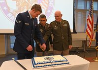 The youngest member of the New Hampshire National Guard, Airman 1st Class Keegan Werner of the 157th Air Refueling Wing, joins NH Adjutant Gen. David Mikolaities and the oldest member, Army Col. James Kelly of Joint Force Headquarters, for a birthday cake-cutting ceremony Dec. 13, 2023, at the Edward Cross Training Complex in Pembroke, N.H.