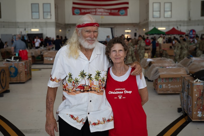 A man and a woman pose for a photo in an aircraft hangar