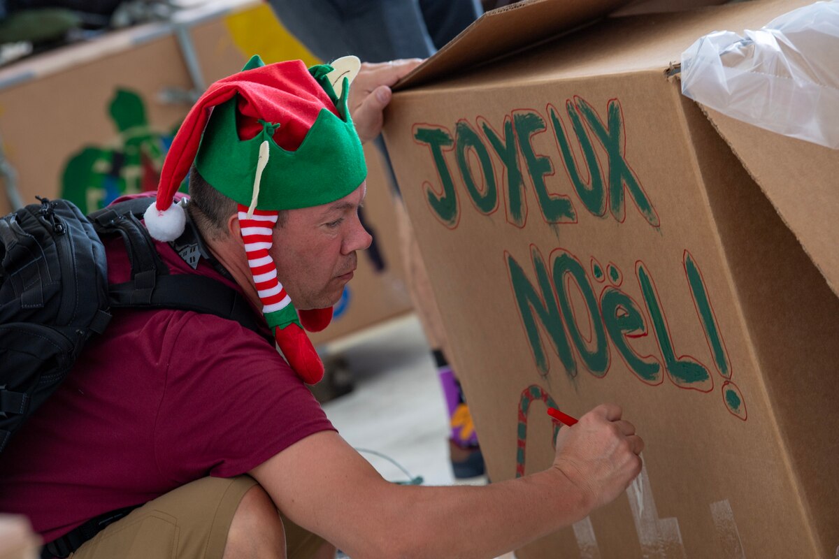 A man decorates a box with holiday messages