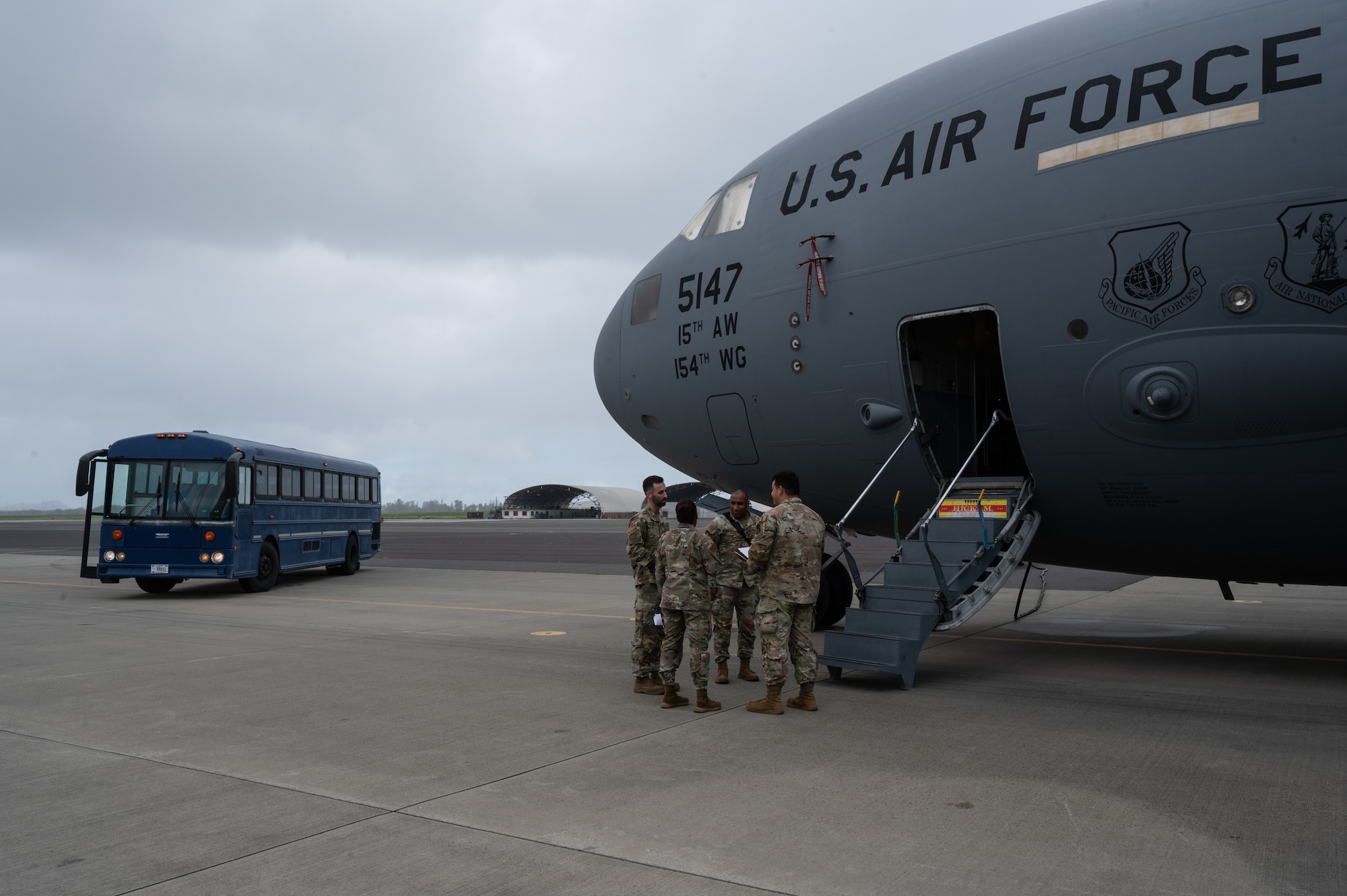 Airmen assigned to Joint Base Pearl Harbor-Hickam discuss deployer procedures outside of a C-17 Globemaster III during the Readiness Exercise 24-01 at JBPHH, Hawaii, Dec. 12, 2023. The 15th Wing trains to operate, fight and advance its capabilities through realistic training exercises designed to test and develop joint logistics, resilience and rapid strategic mobility. (U.S. Air Force photo by Staff Sgt. Alan Ricker)