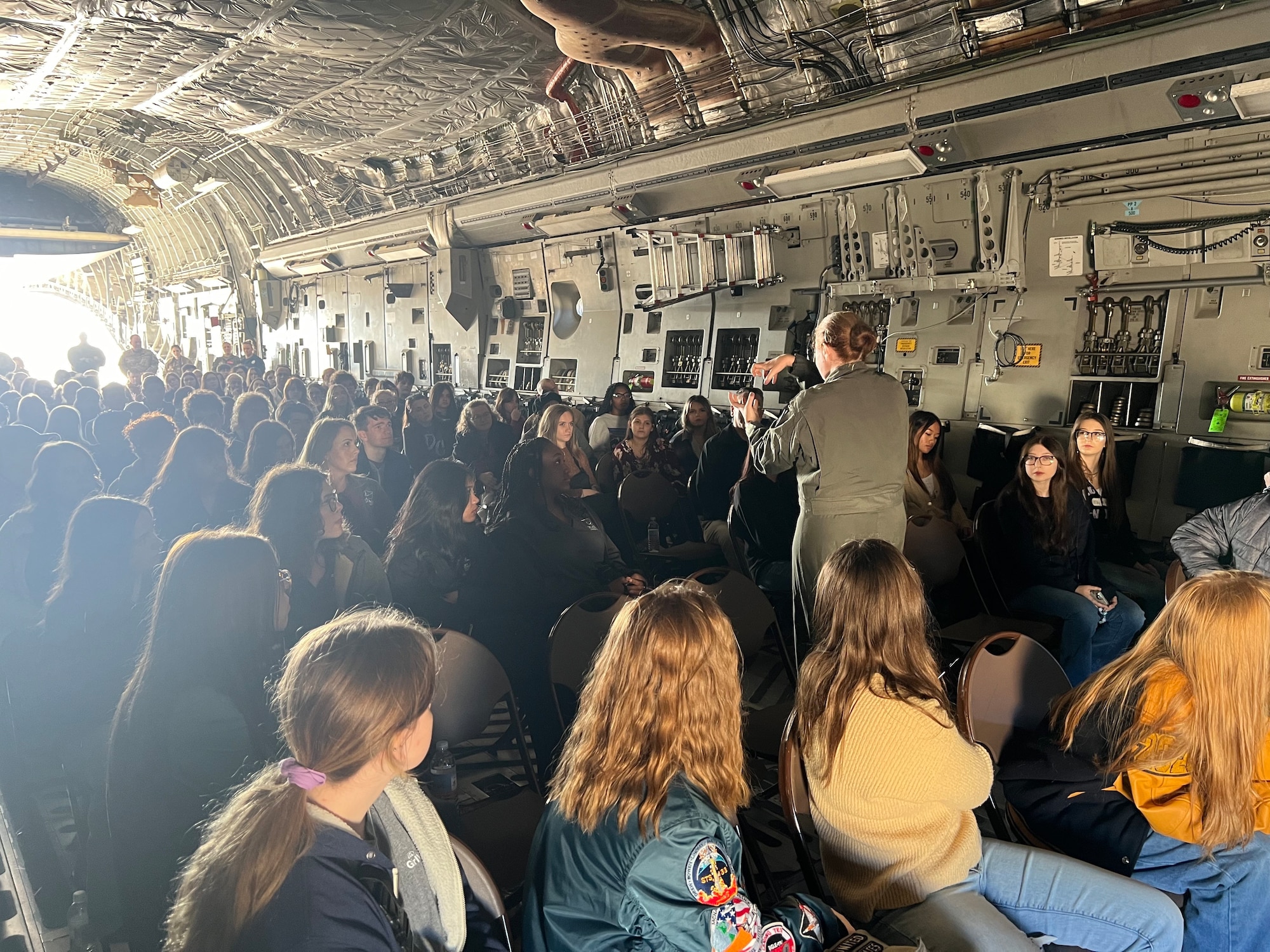 U.S. Air Force Staff Sgt. Jackie Mermolia, 58th Airlift Squadron loadmaster instructor, talks to students inside a C-17 Globemaster III aircraft at the 2023 Oklahoma Women in Aviation and Aerospace event at Will Rogers Air National Guard Air Base, Oklahoma, Dec. 8, 2023. Students from all over Oklahoma attended the event that was held to highlight the contributions of women in aviation and aerospace career fields in Oklahoma. (Courtesy photo by U.S. Air Force Maj. Megan Edson).