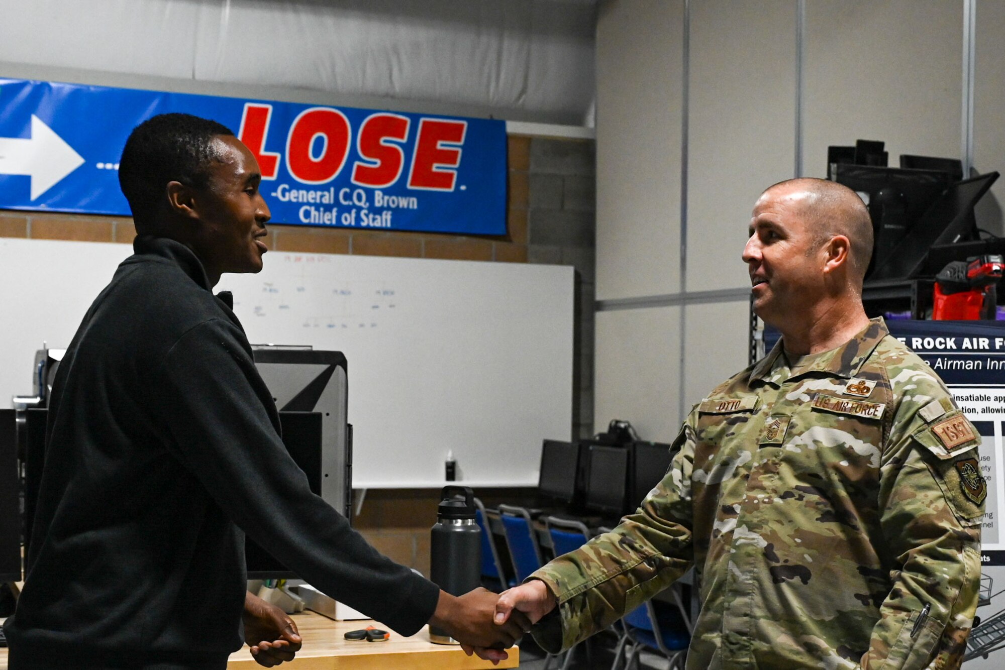 Two military members shake hands.