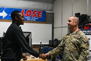 Two military members shake hands.