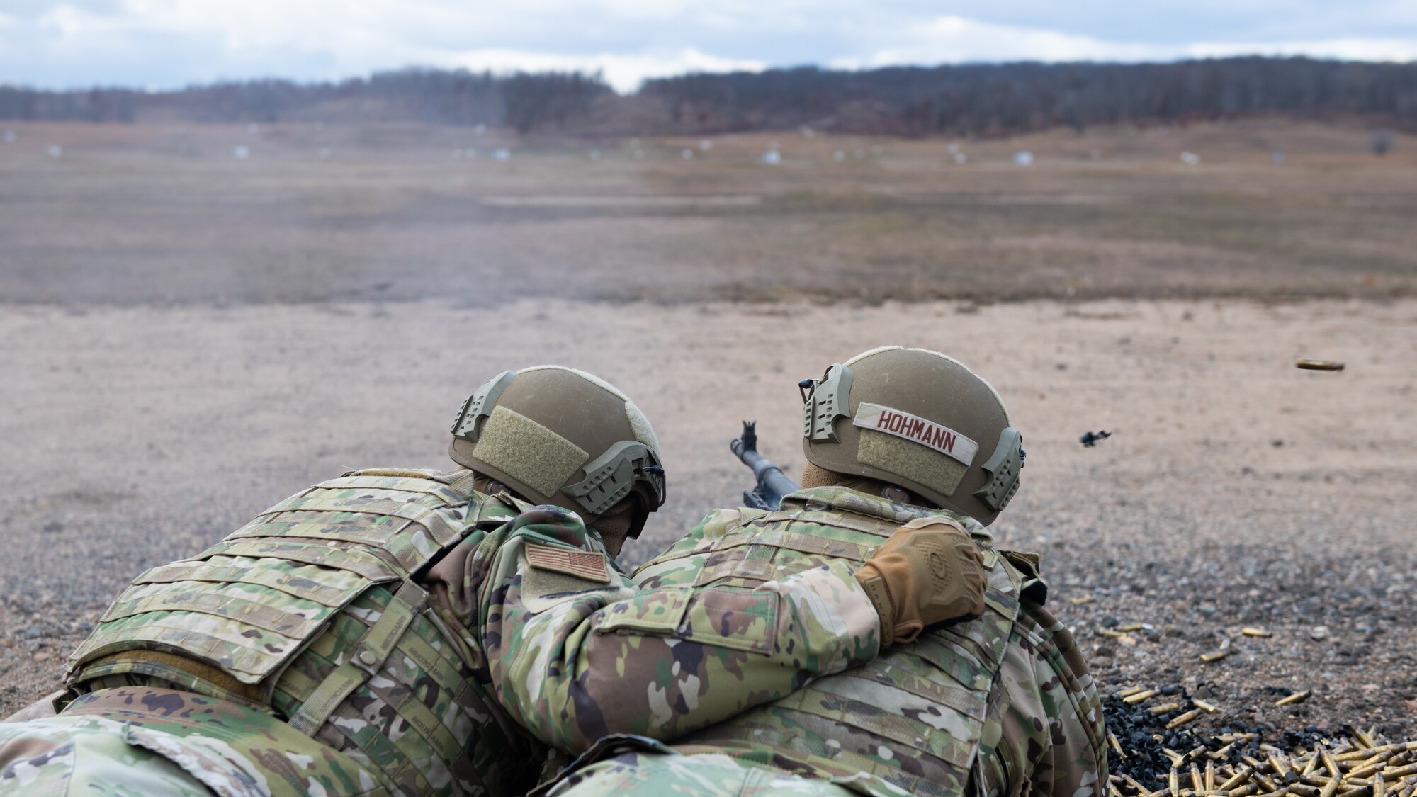 Two men view a shooting range through their machine gun view finder.