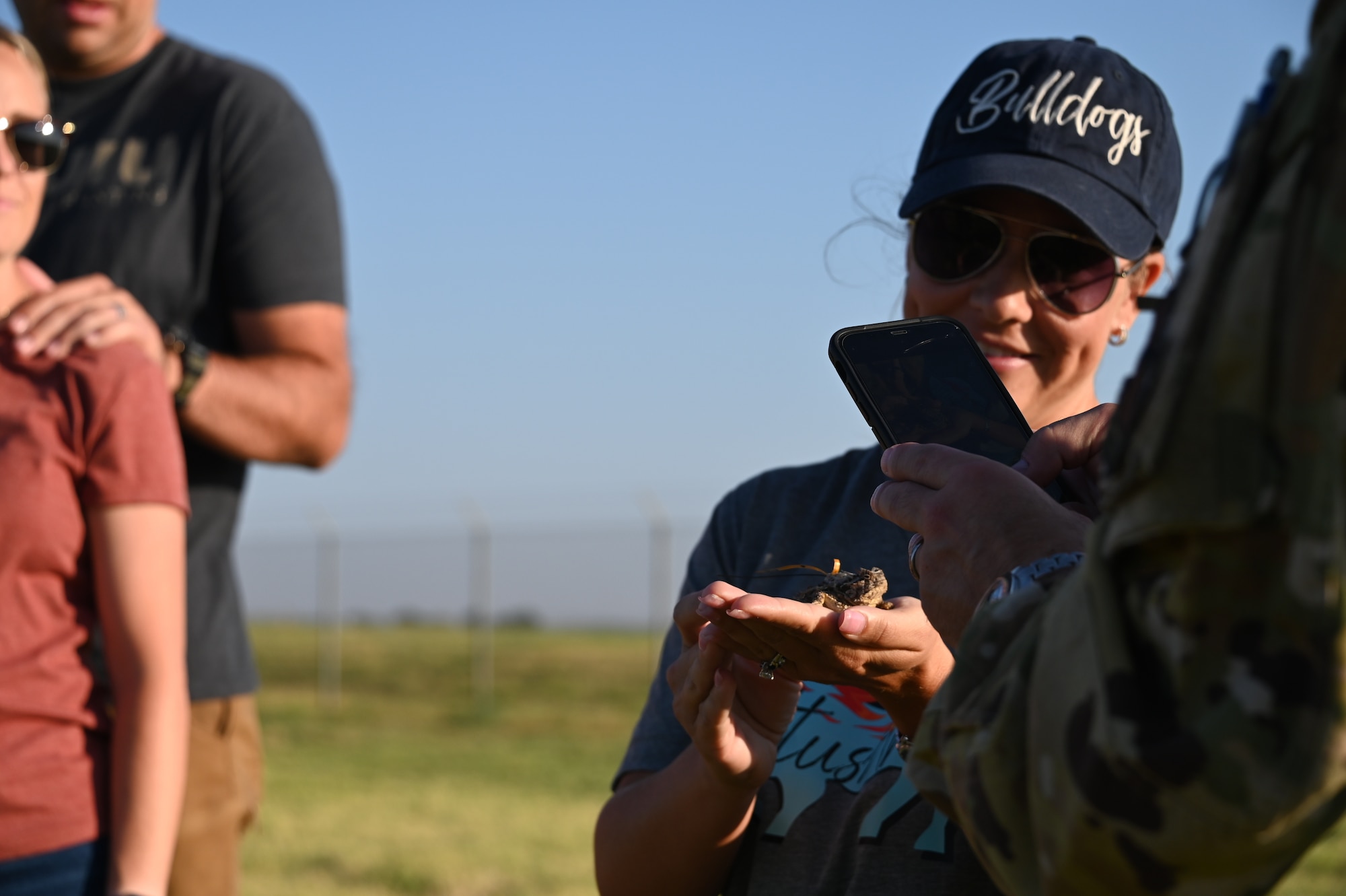 U.S. Air Force Col. Jeff Marshall, 97th Air Mobility Wing (AMW) commander, takes a photo of a Texas horned lizard in the hands of Brenna Marshall, 97th AMW key spouse, at Altus Air Force Base, Oklahoma, Sept. 9, 2023. The Texas horned lizard is a protected species and can be found throughout Oklahoma, Texas, Kansas, New Mexico, and Mexico. (U.S. Air Force photo by Airman 1st Class Kari Degraffenreed)