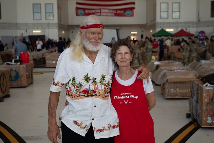 A man and a woman pose for a photo in an aircraft hangar