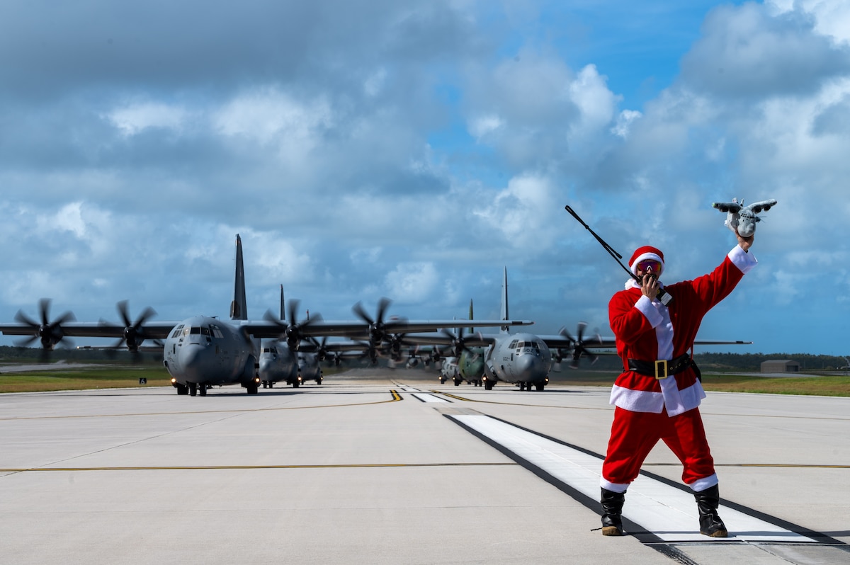 A man dressed as santa stands in front of several C-130 aircraft
