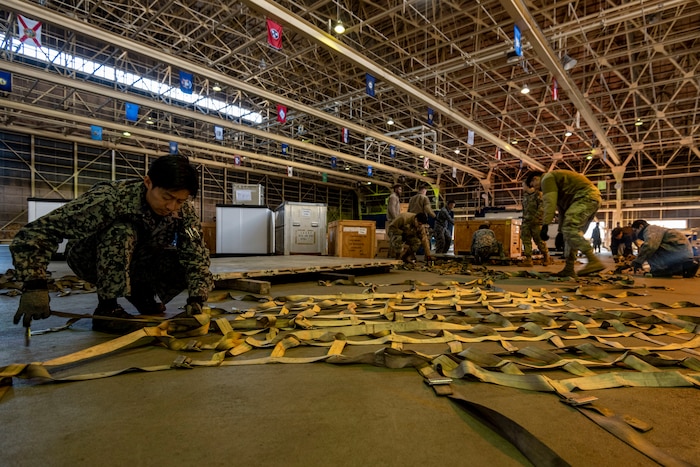 A Japan Air Self-Defense Force member lays out securing straps during a Port Dawg Challenge at Misawa Air Base, Japan, Dec. 8, 2023.