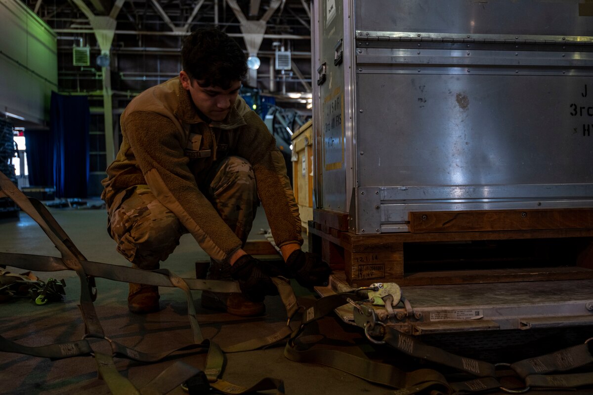 A 35th Logistics Readiness Squadron member attaches securing straps to a cargo pallet during a Port Dawg Challenge at Misawa Air Base, Japan, Dec. 8, 2023.