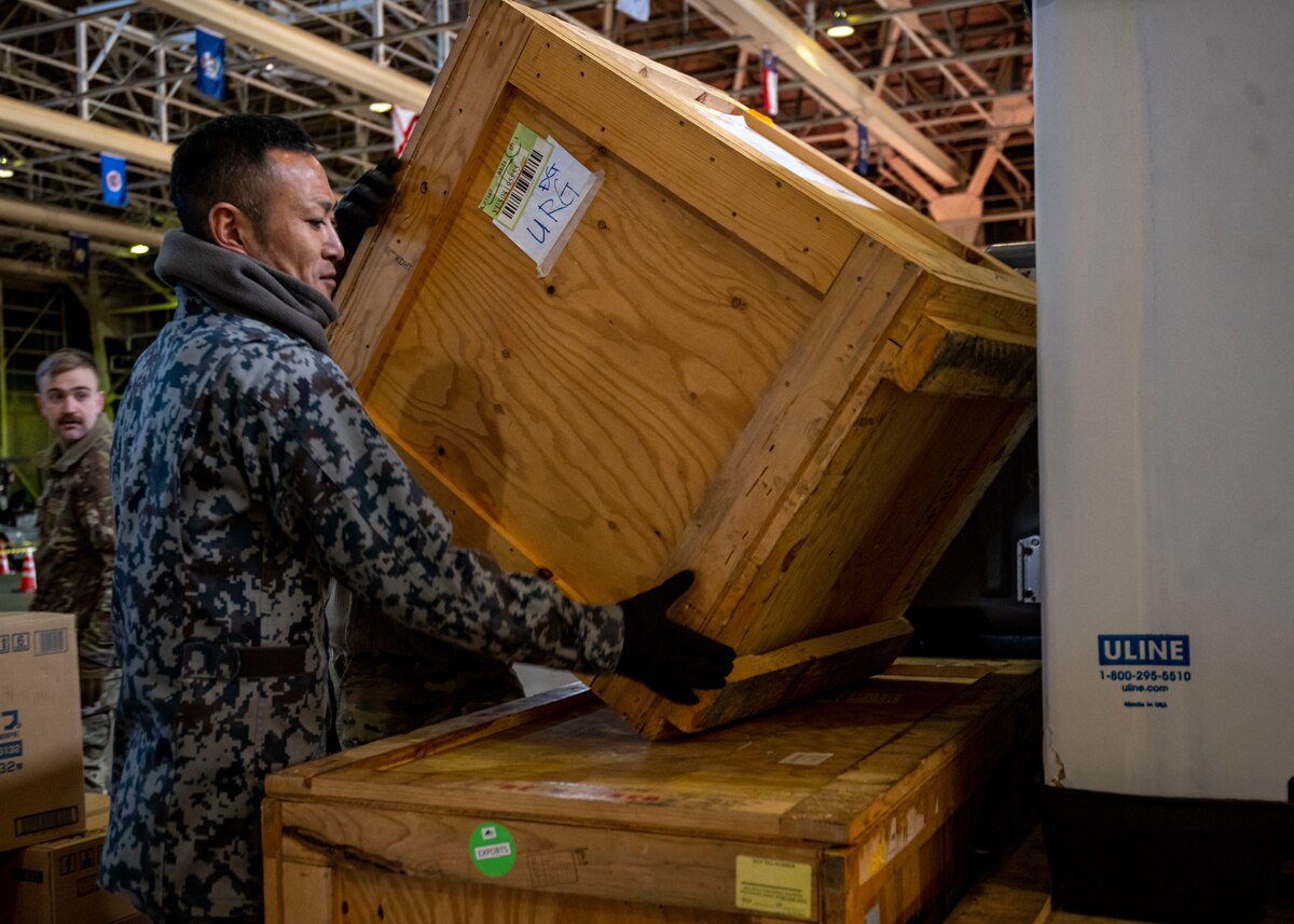 A Japan Air Self-Defense Force member sets a wooden box on a pallet during a Port Dawg Challenge at Misawa Air Base, Japan, Dec. 8, 2023.