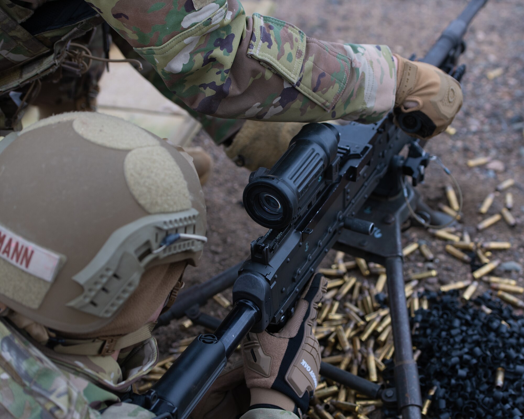 2 men hold machine gun.