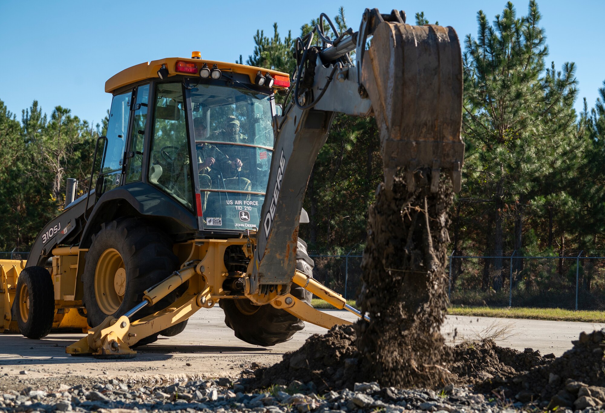 U.S. Air Force Col. Paul Sheets, 23rd Wing commander, empties a backhoe