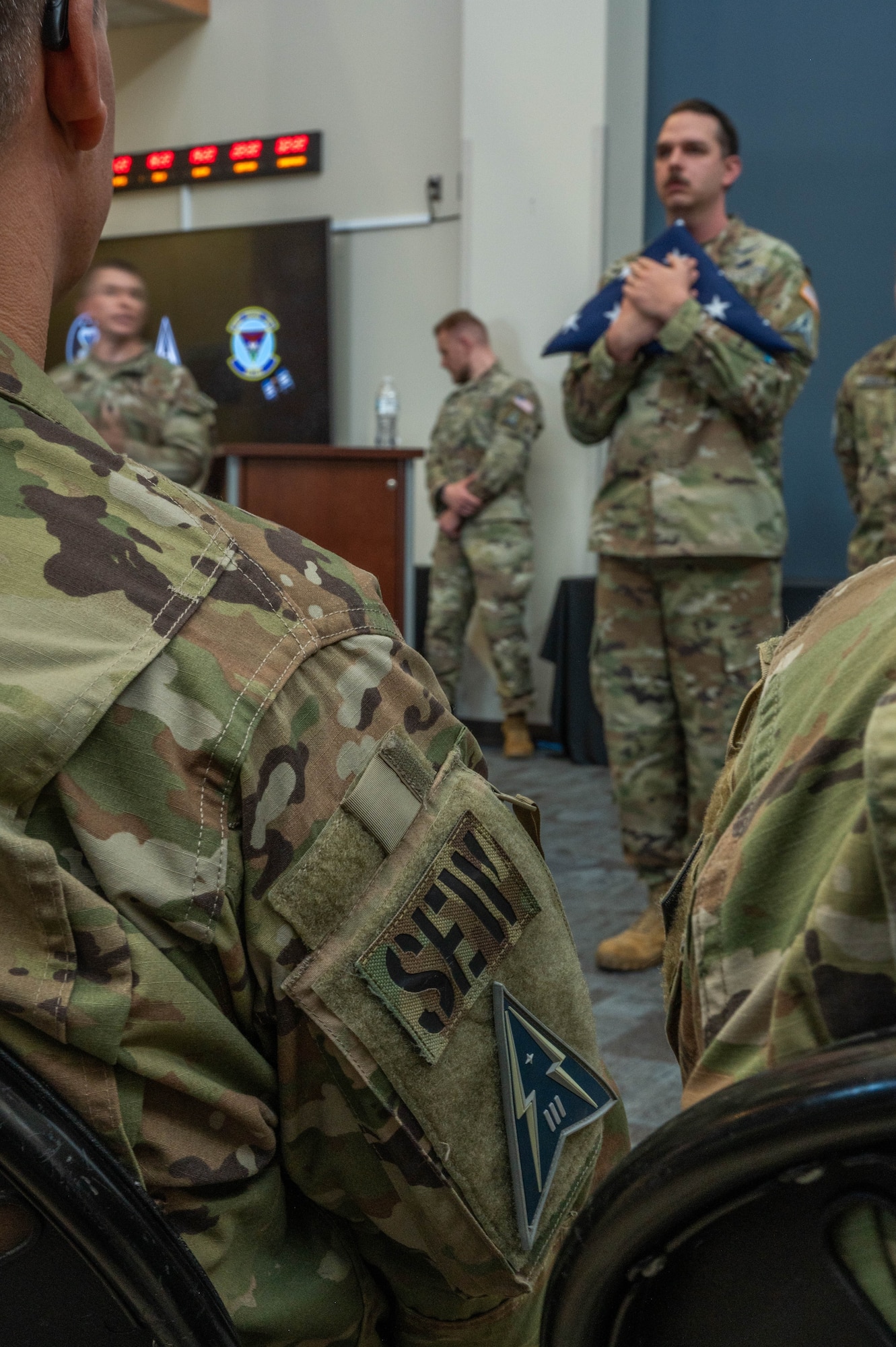 A member of the 16th Electromagnetic Warfare Squadron, a subordinate unit under Space Delta 3 – Space Electromagnetic Warfare, holds one of three folded American flags during the 16 EWS’ Flag Folding Ceremony at Peterson Space Force Base Dec. 7, 2023. The ceremony celebrated Guardians and Air Force Reservists from the 160th, 161st, and 162d Deployment teams ahead of their upcoming deployments.