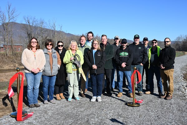 Group of people stand with oversized scissors.