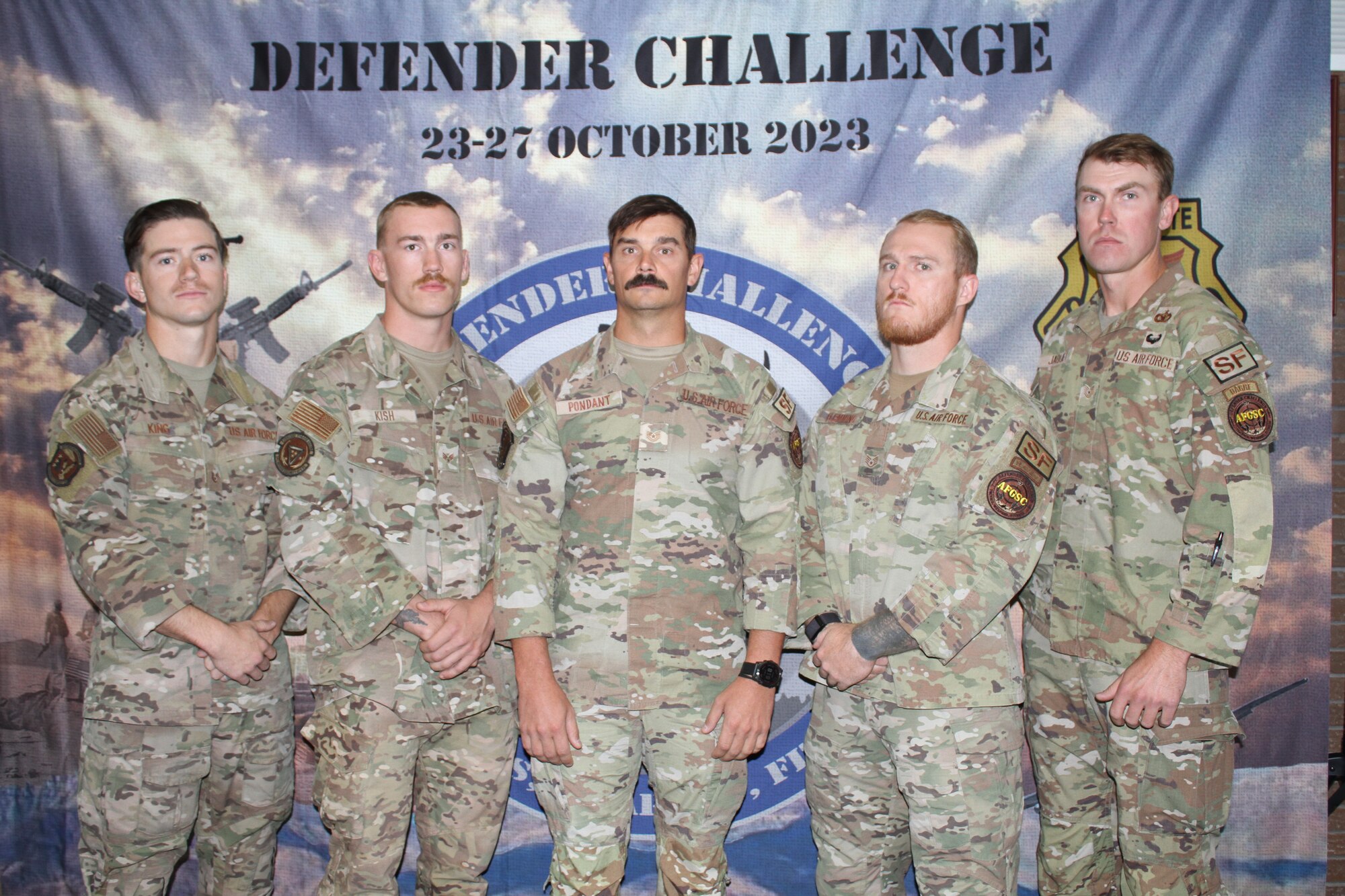 group photo of defenders in front of a banner reading Defender Challenge 23-27 October