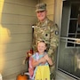 Soldier in uniform standing with a little girl on a porch