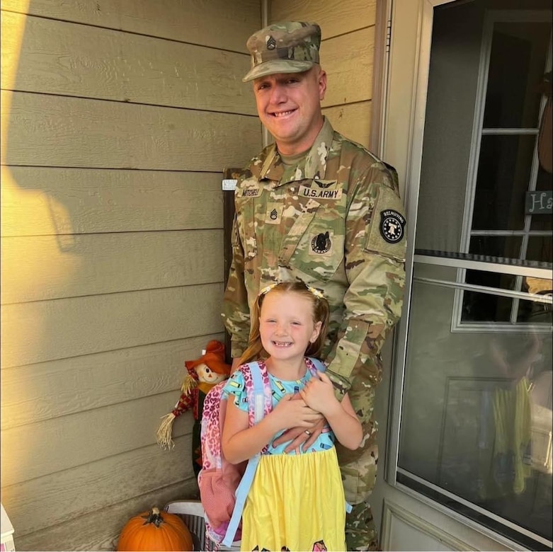Soldier in uniform standing with a little girl on a porch