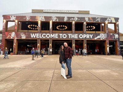 Man and women stand in front of the Grand Ole Opry