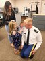 Soldier in uniform getting patches put on by his son and daughter. The Soldier's wife is standing behind the kids.