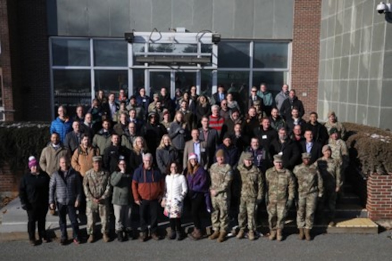 Dozens of people stand in front of a building to pose for a photo.