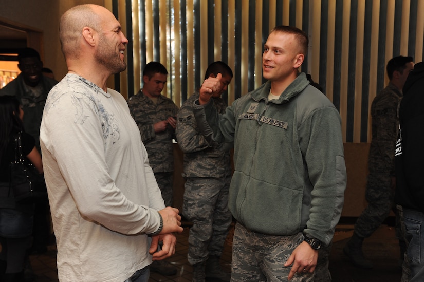 A person dressed in civilian clothing chats with a young service member.
